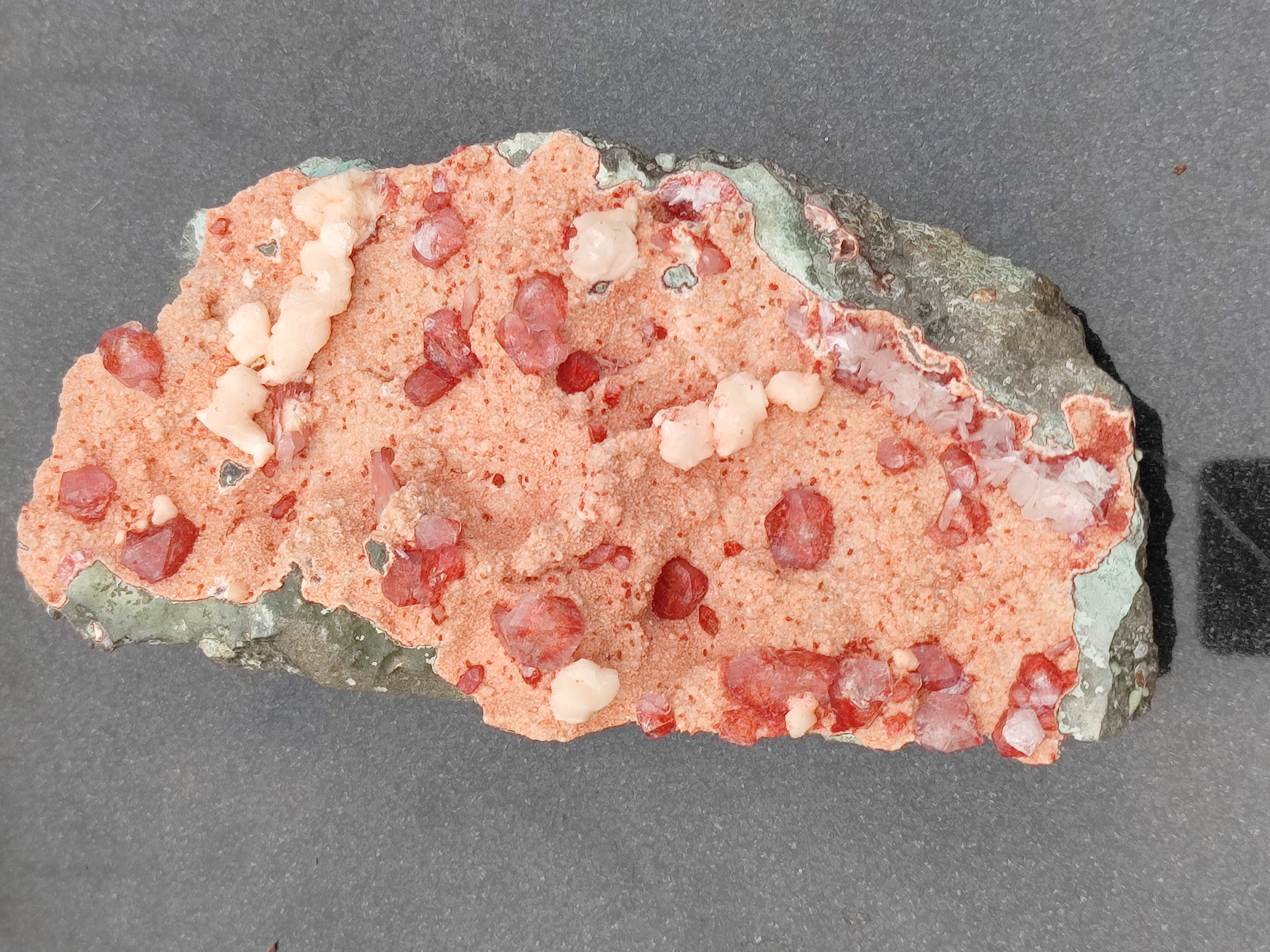 Crystalline Tutti Frutti Icecream
Nature’s Sweetest Sculpture in Stone

A marvel of mineral magic, the Crystalline Tutti Frutti Icecream is a naturally occurring gemstone cluster that resembles a scoop of the beloved Italian dessert—bursting with color, texture, and joyful energy. Formed over millennia, this specimen is a celebration of Earth’s playful artistry, blending coral-pink rhyolite, ruby-red garnet-like crystals, and creamy white chalcedony nodules into a composition that feels both delicious and divine.

💎 Visual Composition

Coral-pink rhyolite base with a granular, frosted texture

Scattered ruby-red translucent crystals, reminiscent of garnet or spinel, glistening like candied fruit

Smooth, rounded white chalcedony nodules, adding creamy contrast and balance

Encased in a rugged greenish-gray border, grounding the vibrant interior with earthy elegance

🔮 Metaphysical Resonance

Stimulates joy, creativity, and emotional warmth

Balances heart and sacral chakras, encouraging playfulness and passion

Ideal for uplifting spaces, inspiring artistic flow, and celebrating inner light

🌿 Suggested Placement Display in creative studios, healing spaces, or joyful corners of your home. Its candy-like appearance and radiant energy make it a perfect centerpiece for those who seek beauty with meaning.

🧘‍♀️ Recommended Ritual Hold the stone during moments of self-expression or celebration. Let its vibrant hues remind you of life’s sweetness and the magic of being fully present.